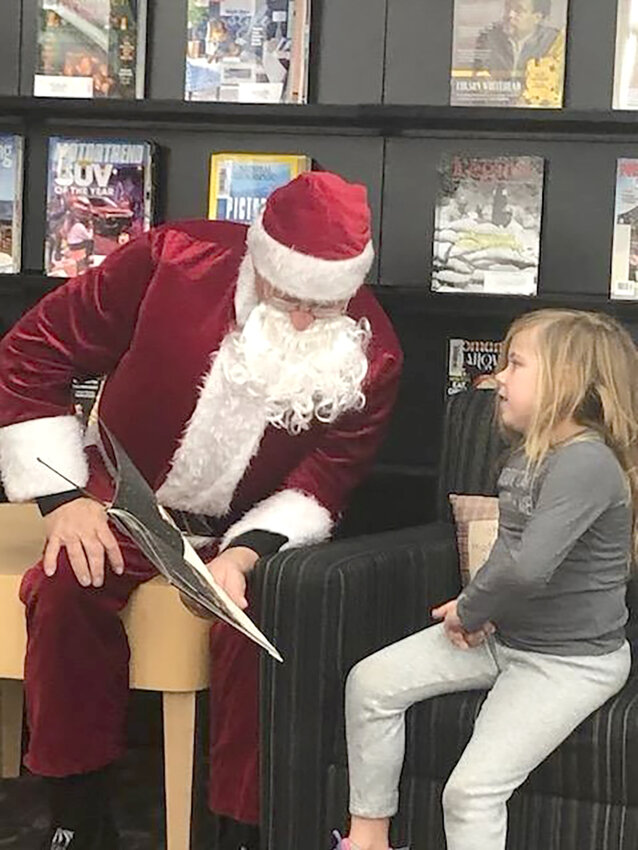 Kent Bovenmyer, a.k.a Santa, reads to Emma Harris in the Wilton Public Library. Photo by Rebecca Bovenmyer