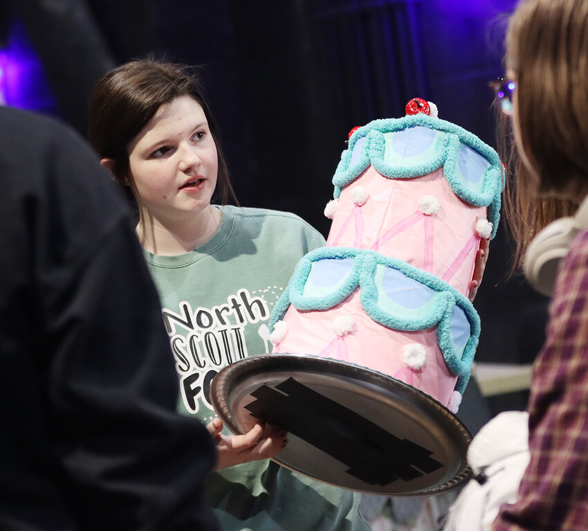 Haidyn Koberg examines a cake prop for the &quot;Be Our Guest&quot; scene.