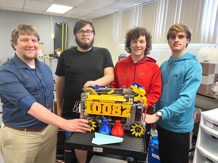 Ssenior members of the Durant High School robotics team join teacher Joey Kramer, on left, as they pose with their robot &ldquo;Fire Fox&rdquo; which took the seven-member team to state for the first time last month. From right are Landon Marth, Cayden Eckhardt and Ian Heick. Photo by Tim Evans