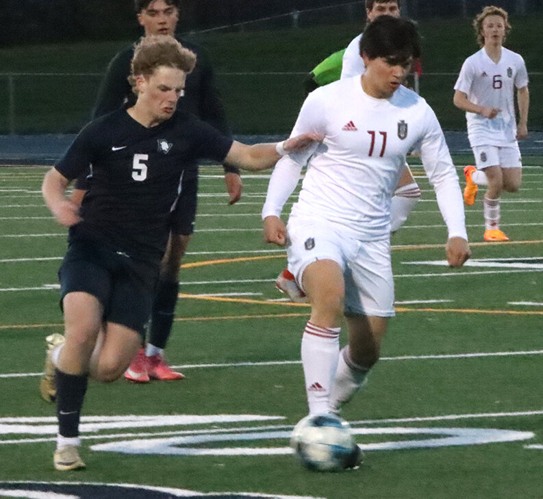 Lancer junior forward Chase Smith dribbles the ball away from Spartan junior Jack Reiter.