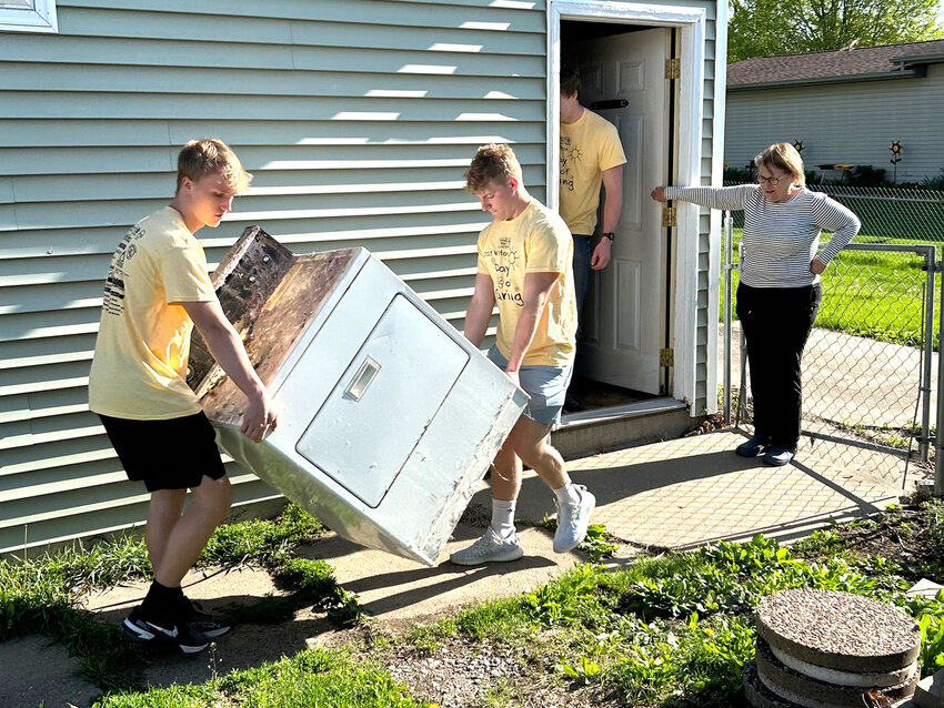 Then Wilton High School seniors, Clayton Guyer, on left, and Max Yohe help a resident take a dryer out of her house as part of last year&rsquo;s Wilton Day of Caring