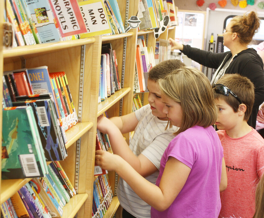 Kids choose new titles during the Scott County Library Bookmobile's June 10 stop in Donahue.