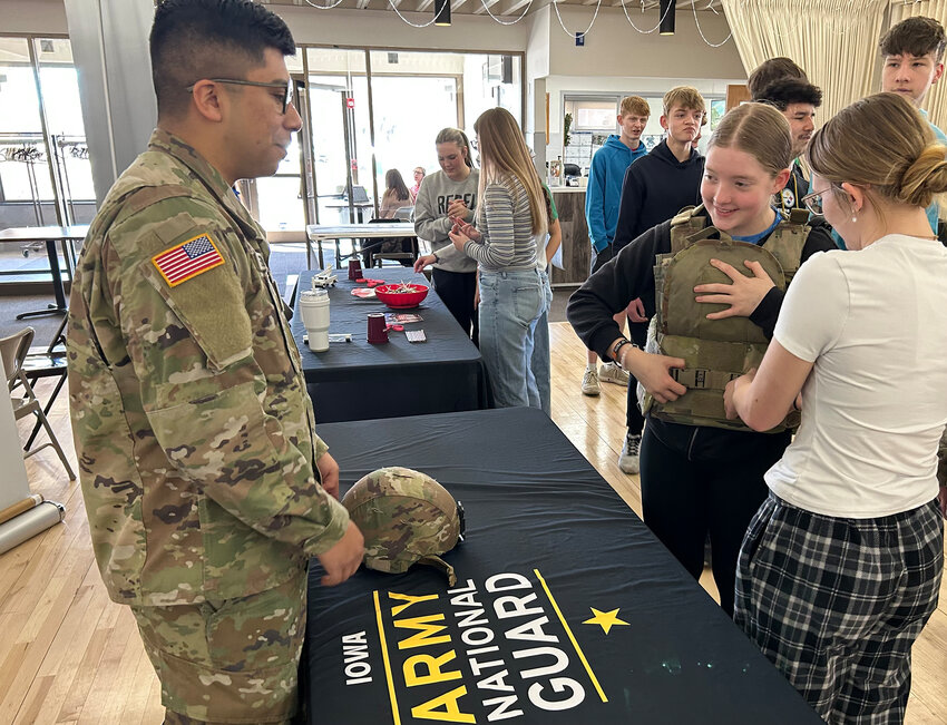 Staff Sgt. Fernandez shows Durant student Jenna Louder just how heavy military gear can be at the National Guard booth.