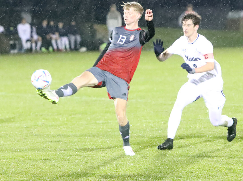 In the rain, Lancer senior Isaac Stanley plays keep-away from Cedar Rapids Xavier captain Owen Vasquez.