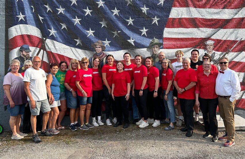 Candy Kitchen employees, event volunteers, and members of the Ochiltree family all gather around the Candy Kitchen veterans memorial for a photo.