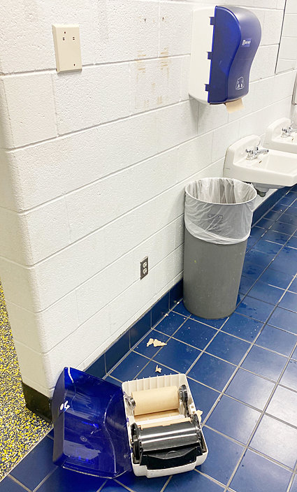 A paper towel dispenser was pulled from the wall and discarded to the floor.