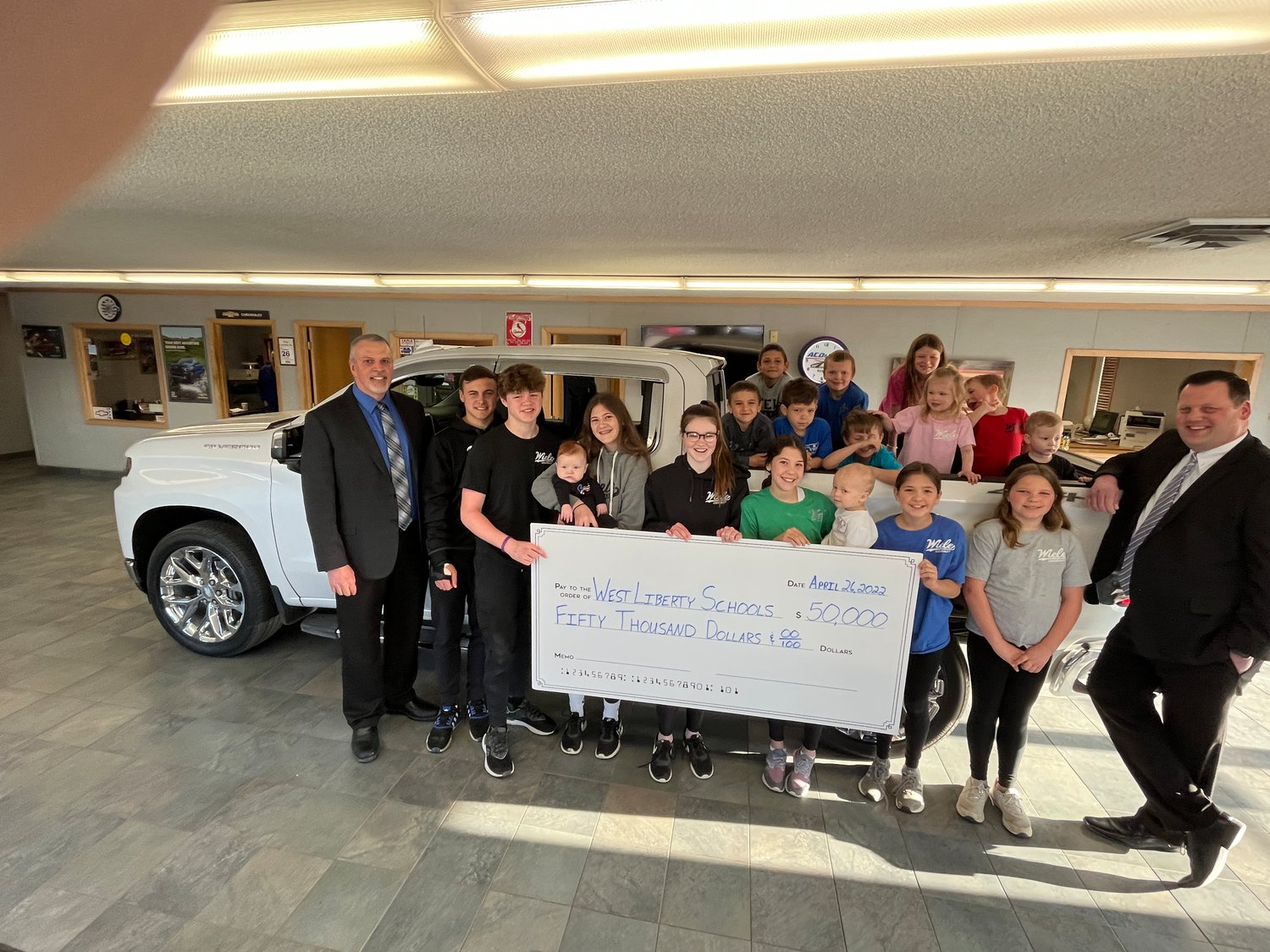 West Liberty School Superintendent Shaun Kruger, on left, and Activities Director Adam Loria join the children and grandchildren of the Wiele families that have owned the Wiele Chevrolet dealership in West Liberty for more than seven decades. The dealership presented a $50,000 check toward construction of the new athletic complex and fields to be built at West Liberty High School.