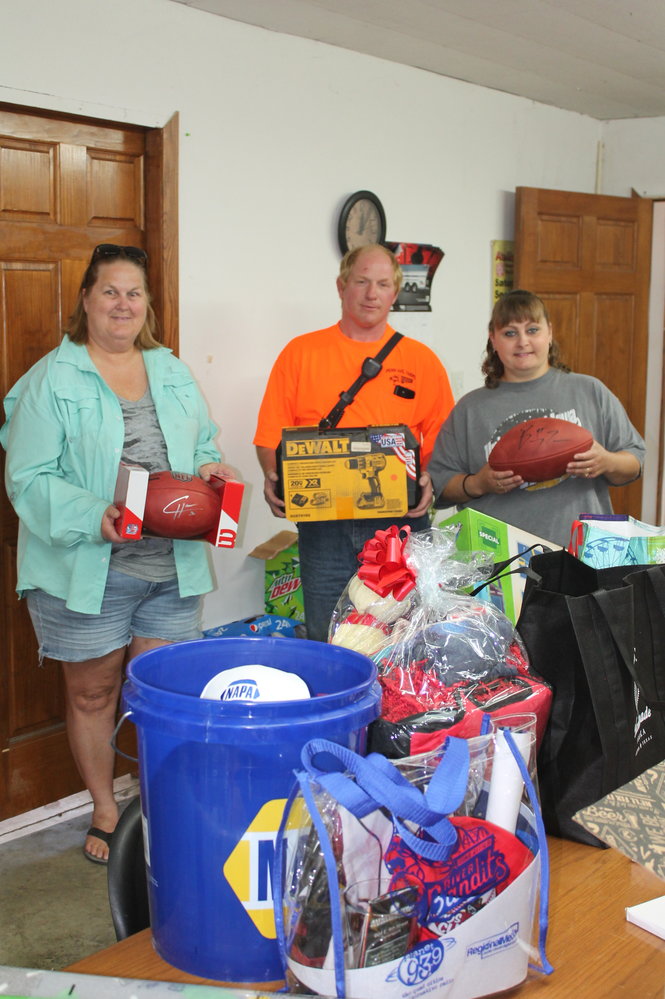 The Atalissa Fire Department hopes to raise thousands of dollars this weekend to put toward a new tanker fire truck with their Atalissa Day fundraiser that includes all kinds of family activities and fun. Here, Gina and Scott Skubal as well as Karen Feddersen show some of the items to be presented for the live auction to begin at 6 p.m. at the fire station including autographed NFL footballs.