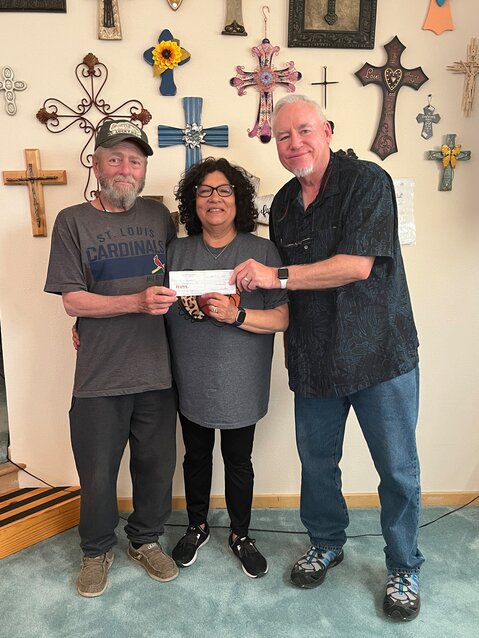 Preacher Mike James (left) of the Nazarene Church in Stinnett presents $5,000 to the Mondin Family.