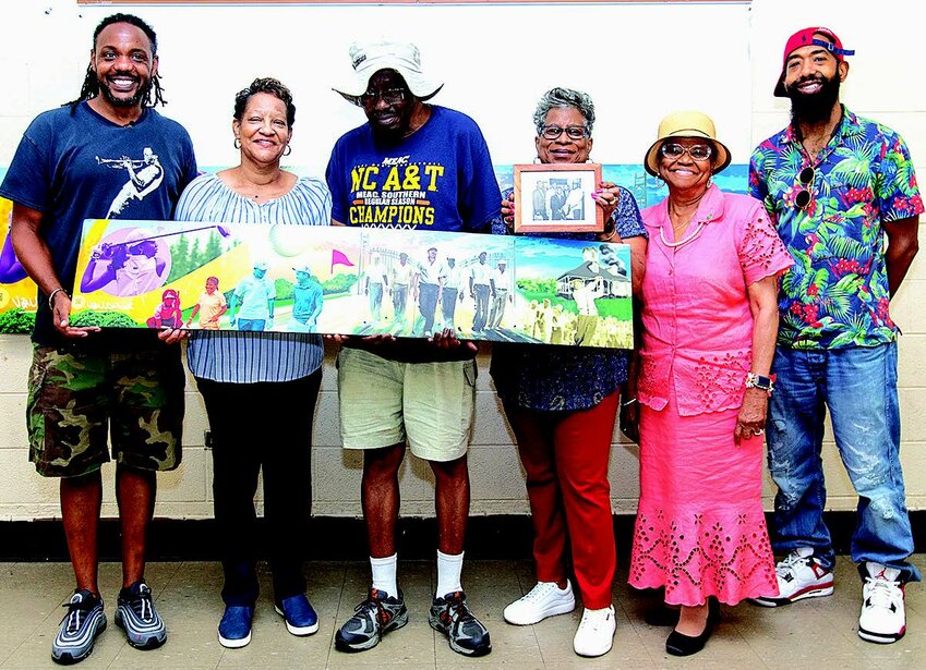 Hold a rendering of the Greensboro Six mural during a public input session are (L-R): artist Vincent Ballentine, City Councilmember Sharon Hightower, Richard Herring, brother of Greensboro Six member Elijah Herring; Marjorie Murray Bryant, daughter of Greensboro Six member Samuel Murray; City Councilmember Goldie Wells and mural artist Andre Trenier.