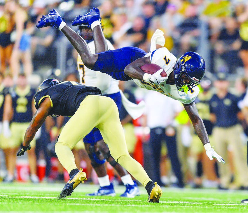 A&T running back (#7) Kenji Christian leaps over a Wake Forest defender at Saturday’s (Aug. 31) opening game.