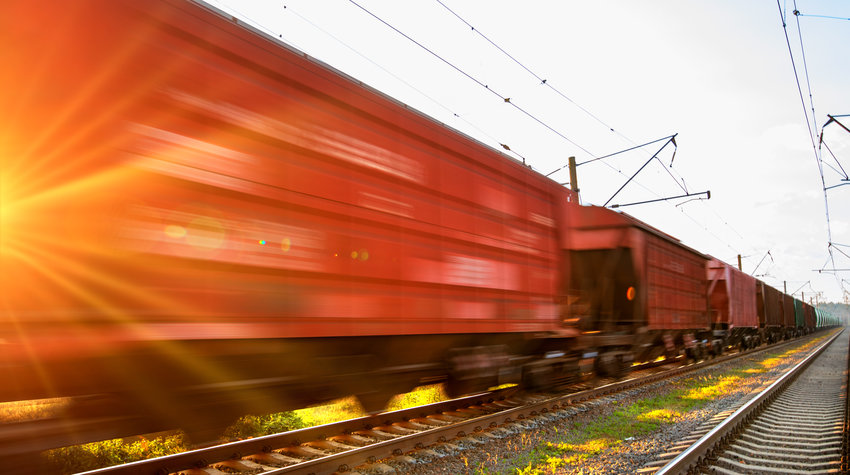 The train with freight cars moves by rail at high speeds.