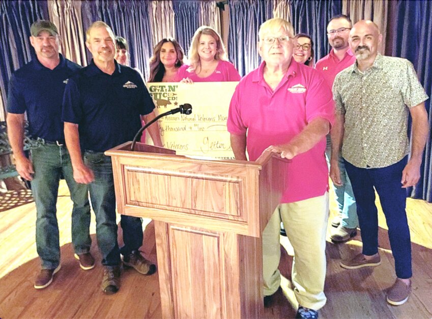 Missouri's National Veterans Memorial founder James Eddleman (front, right) and members of the MNVM board receive a check for $60,000 from the Gettin' Sauced Barbecue Competition committee during an appreciation banquet on Thursday, June 20, at Richardet Floor Covering in Perryville.