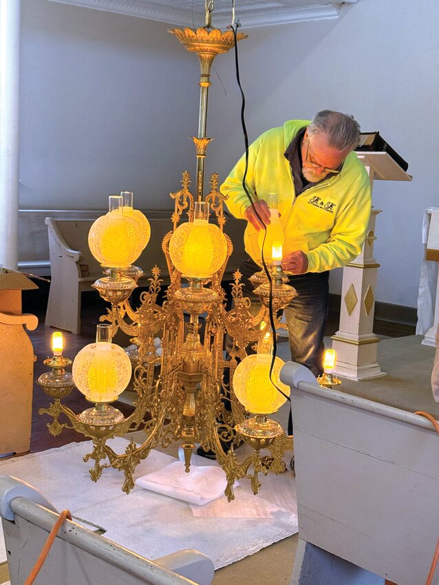 Volunteers carefully carry a restored chandelier into the Hill of Peace Lutheran Church in Friedenberg for installation in the sanctuary’s ceiling where it hung many years ago.