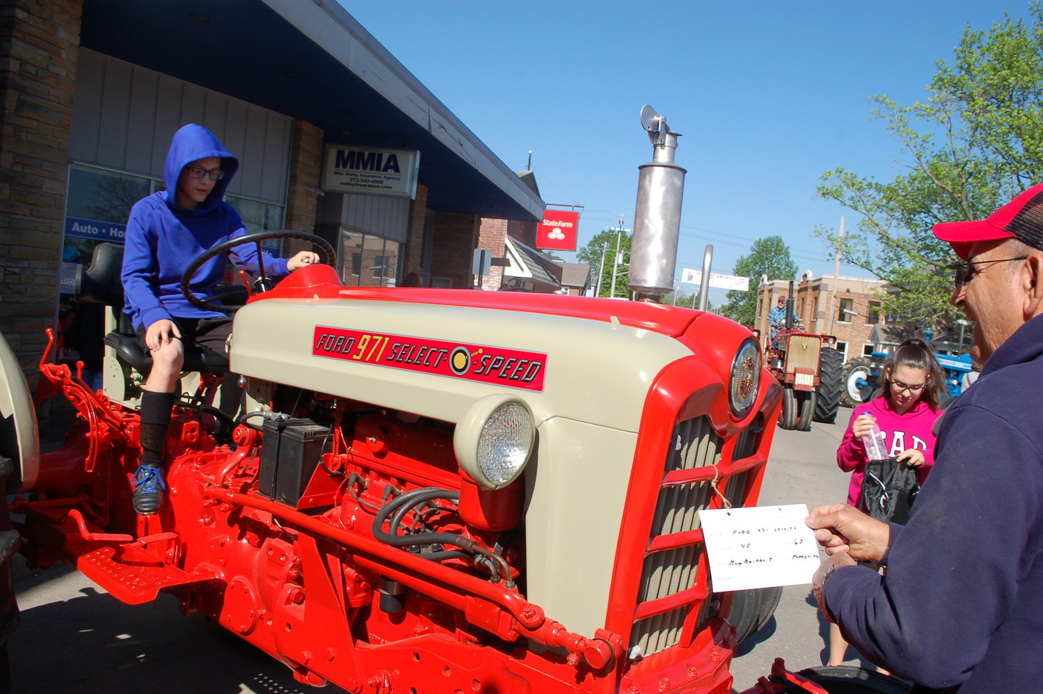 Gary Buchheit, right, of Perryville adjusts the sign on his Ford tractor Saturday morning while (background) another driver brings a tractor to Saturday’s show.
