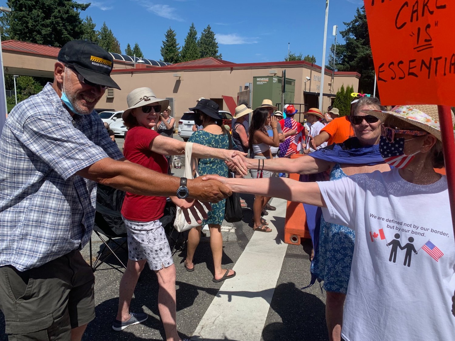 Point Roberts residents and Canadians hold hands across the border at the Boundary Bay border crossing. Demonstrators gathered at the border crossing July 4 to protest against the continued closure of the U.S./Canada border.