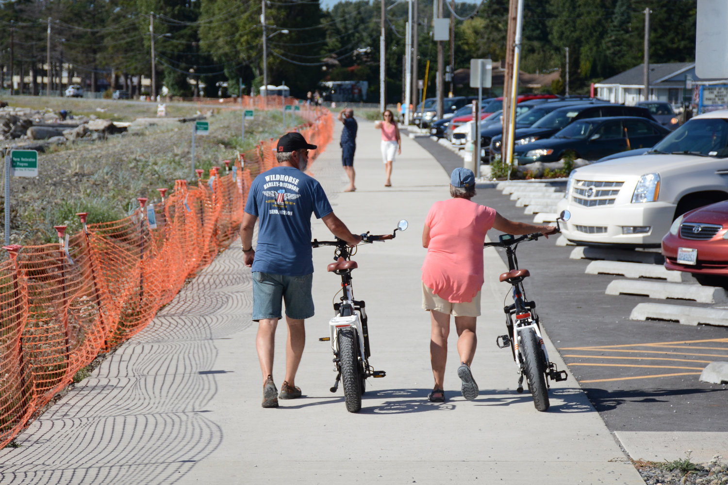 People walk along the Birch Bay berm with their e-bikes.