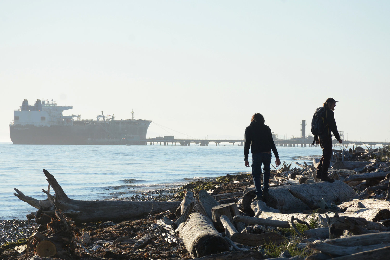 Beachcombers wander down the beach along Gulf Road with a vessel moored at the south wing of BP’s Cherry Point dock last September.