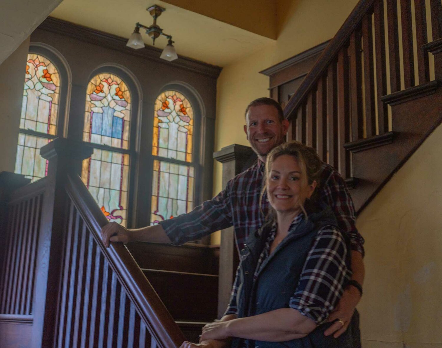 Rachel and Wayne Vezzetti stand on the staircase of their newly purchased historic home. They hope to keep as much of the original detail as possible in the home including the stained glass and wood railings pictured.