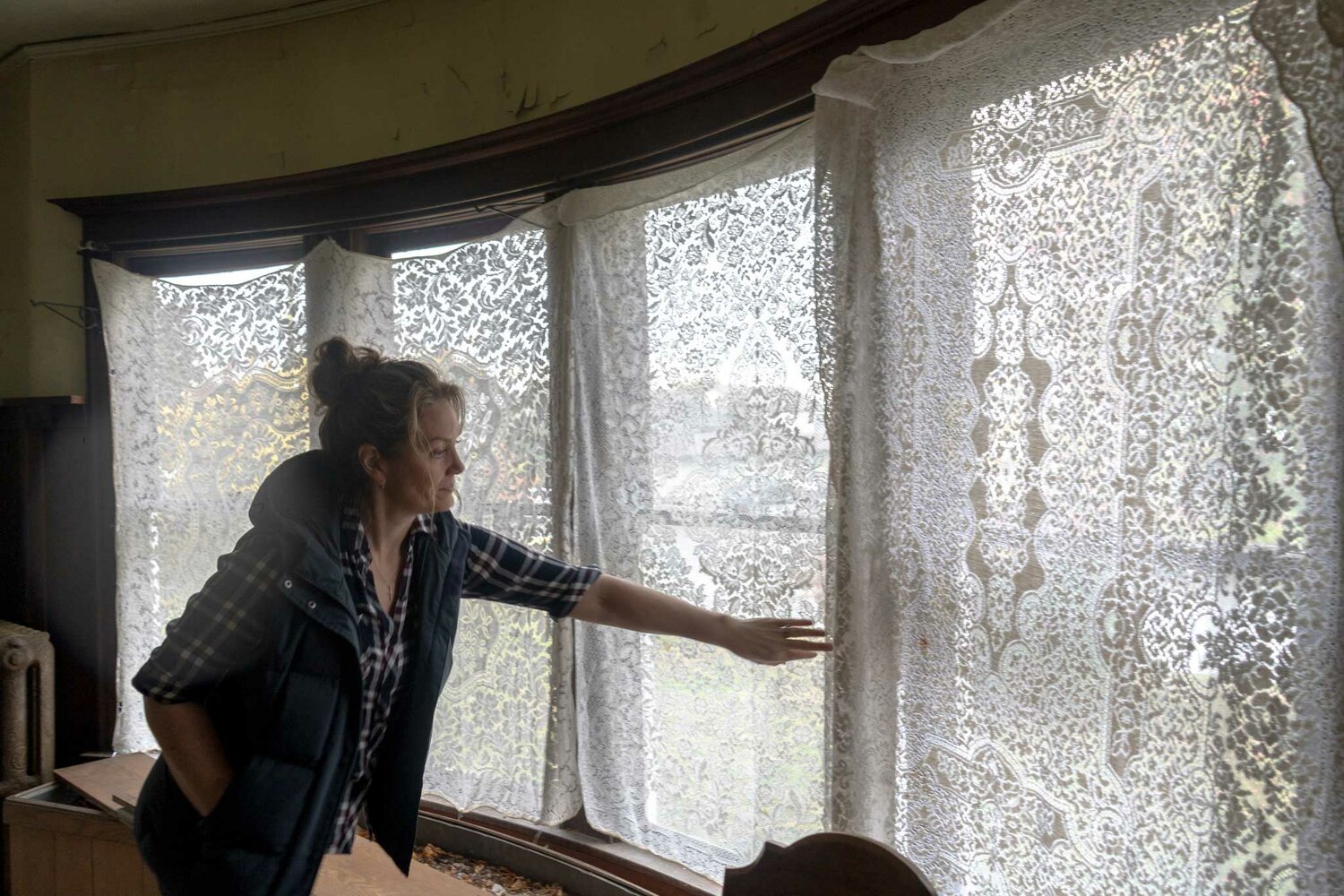 Rachel Vezzetti moves aside the lace curtains in the downstairs of her historic home to show the original curved glass windows. The 1903 home underwent at least one significant renovation in the 1960s and ‘70s but many of the home's original features are intact.