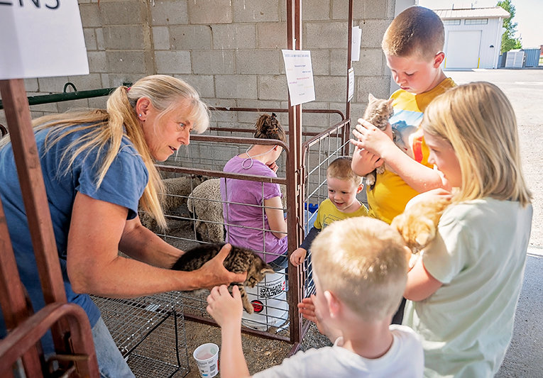 Wendy Smith hands out kittens for cuddling to siblings John, Beth, Jim Tucker and Tommy Black during a recent petting zoo at the Park County Fairgrounds. The petting zoo was part of Powell Library&rsquo;s summer reading program &lsquo;Tales and Tails.