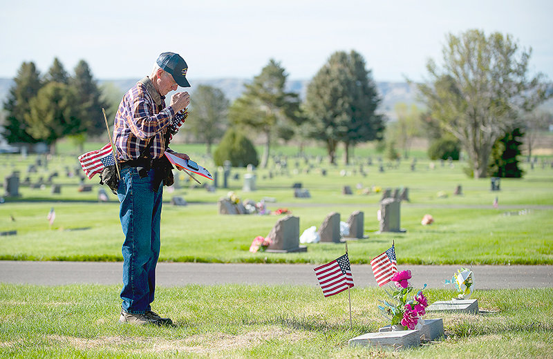 Retired Air Force colonel John Fraser salutes to grave sites of veterans buried at Powell&rsquo;s Crown Hill Cemetery. Volunteers placed American flags at veterans&rsquo; headstones Thursday prior to Memorial Day.