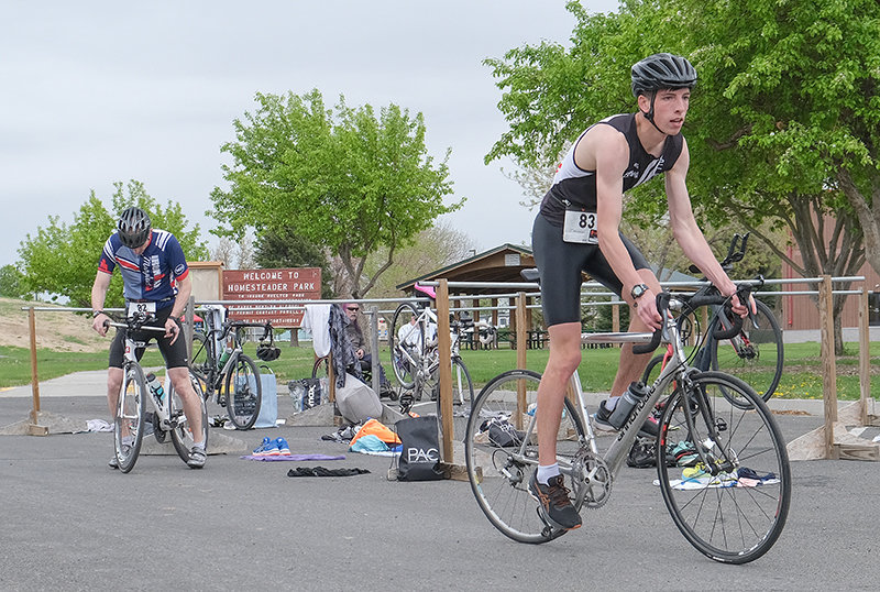 Daniel Merritt (right) hops on his bike as he looks to pull ahead of his dad Ladell Merritt (left) in a little father/son competition during the PAC Triathlon on Saturday.