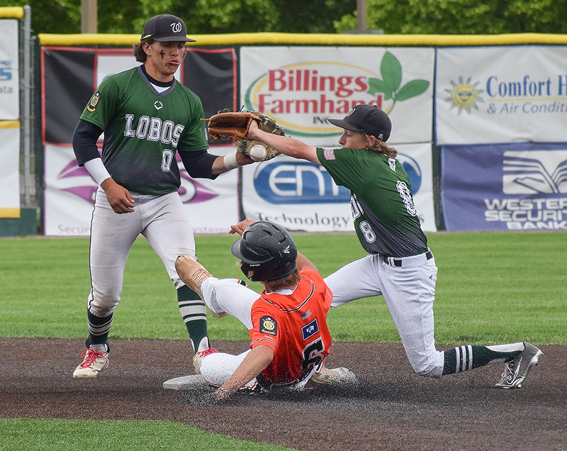 Hoping to create momentum, Dalton Worstell slides down between two defenders to beat the tag during the Billings Cardinals BWW Tournament.