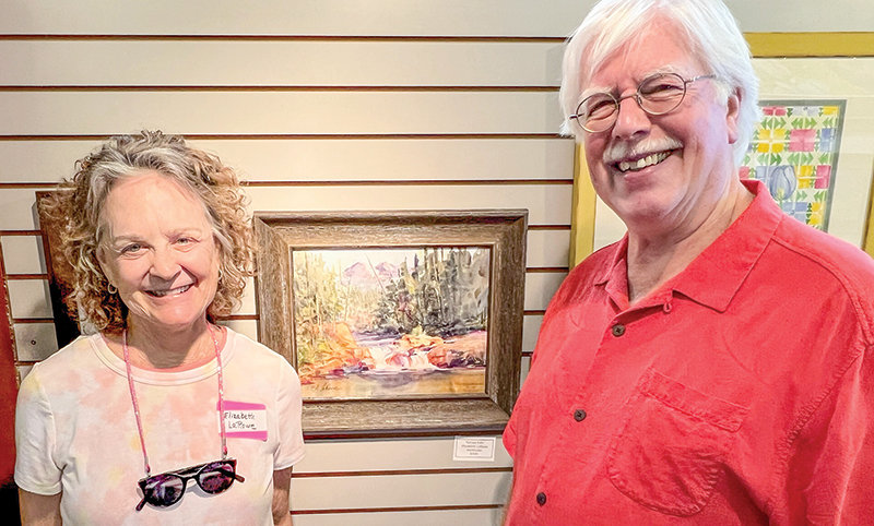 Best of Show recipient Elizabeth LaRowe (left) stands next to her water color painting &lsquo;Kersey Falls&rsquo; with judge Tim Newton.