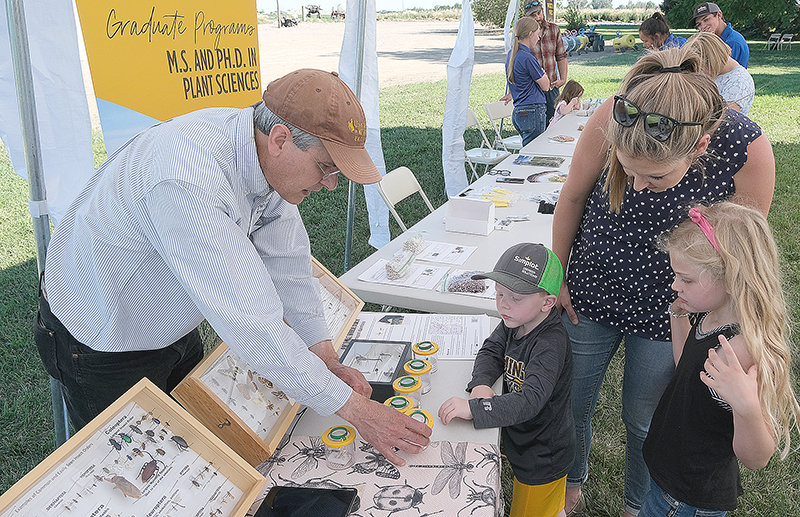 At the annual Powell Research and Extension Center Field Day event, Scott Schell, University of Wyoming Extension entomology specialist, explains some facts about Wyoming insects to Gavin Fulton, Samantha Fulton, and Madison Fulton.