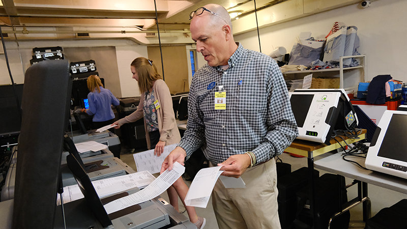 Park County First Deputy Clerk Hans Odde (right) and elections clerk Kaitlyn Johnson insert ballots into voting machines Thursday as part of a public test of the machines ahead of the general election.