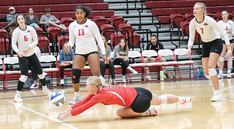 Libero Ellie Thomas gets down to dig a ball while teammates Brooke Palmer (from left), Jocelyn Sanders and Kim Pannell react to her play during the Trappers&rsquo; home match on Oct. 19.