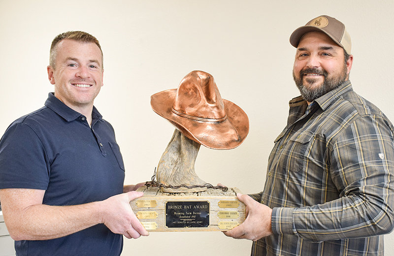 This bronze hat is for sitting, not wearing. It resides in the office of Farm Bureau insurance agent David Gilliatt (left) and was won by Park County Farm Bureau for the most new Century Club Farm Bureau memberships for the year 2022. Brian Asher, president of Park County Farm Bureau, holds up his end (right).