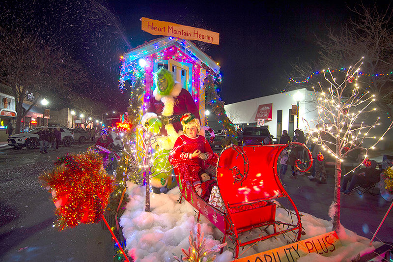 The Heart Mountain Hearing and Mobility Plus float, complete with the Grinch (Chris Pelletier) and Cindy Lou (Gracelynn Gomez, age 9), heads north on Bent Street with the snow flying during the Powell ChristmasFest Parade on Saturday.