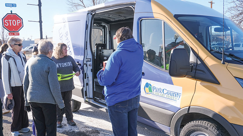Park County Library board chair Pat Stuart (left) and Park County Library Director Karen Horner (holding the ribbon) admire the new Park County Outreach Van along with members of the community.