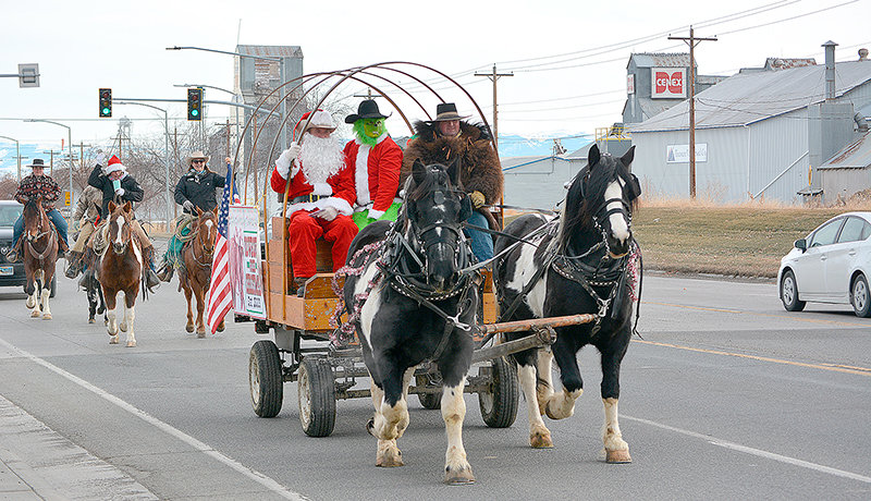 Santa (Mike Apanashk), the Grinch (Caleb Norris) and Jerry Hill (in buffalo robe) lead the Cowboys for Christmas down Coulter Avenue Saturday morning, trailed by (from left in back), Samantha Hill, Rusty Karst (obscured), Cayla Norris and Kristy Lewis on horseback. The group delivered gifts to 13 Powell families.