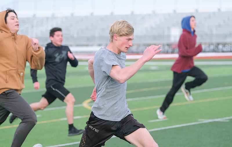 Chance Franks sprints ahead of a group of runners during indoor track practice on the turf Monday.