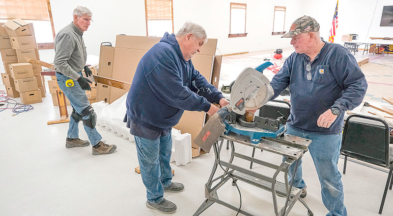 From left, volunteers and veterans Stephen Burtoft, Bud Schrickling and John Frasier work to cut and install hand-finished trim for the hall. It is one of the final touches in the newly renovated hall.