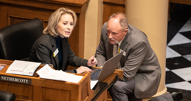 Sen. Tara Nethercott (R-Cheyenne) and Larry Hicks (R-Baggs) speak earlier in the session in the Senate Chamber. The two were on opposite sides of the debate on whether to revive a crossover bill, with Hicks successfully getting it to another committee after it had previously been killed.