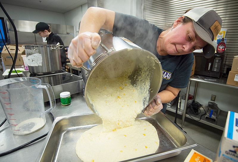Ashley Robichaux, owner of Cajun Phatty&rsquo;s, prepares a tray of cheese and corn grits for the Mardi Gras meal Saturday.