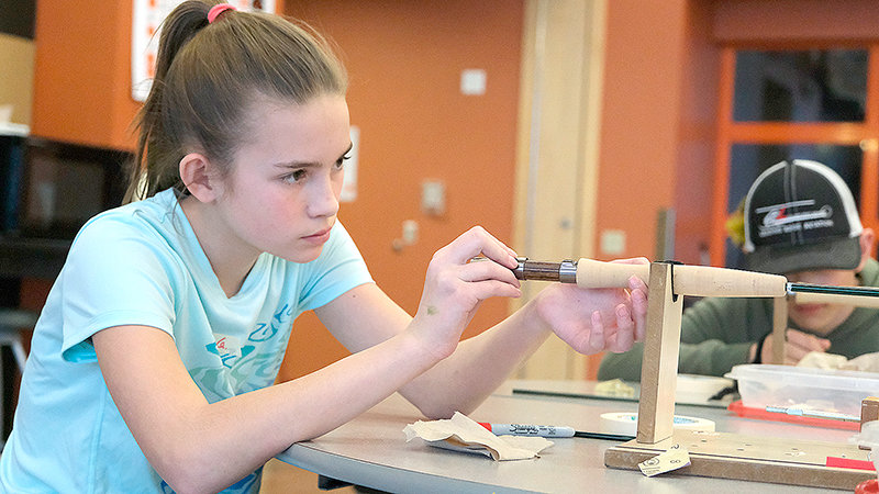 Hailee Gorsuch, a mentor in the Fly Fishing Club, shows intense focus while she assists with building rods on Friday.