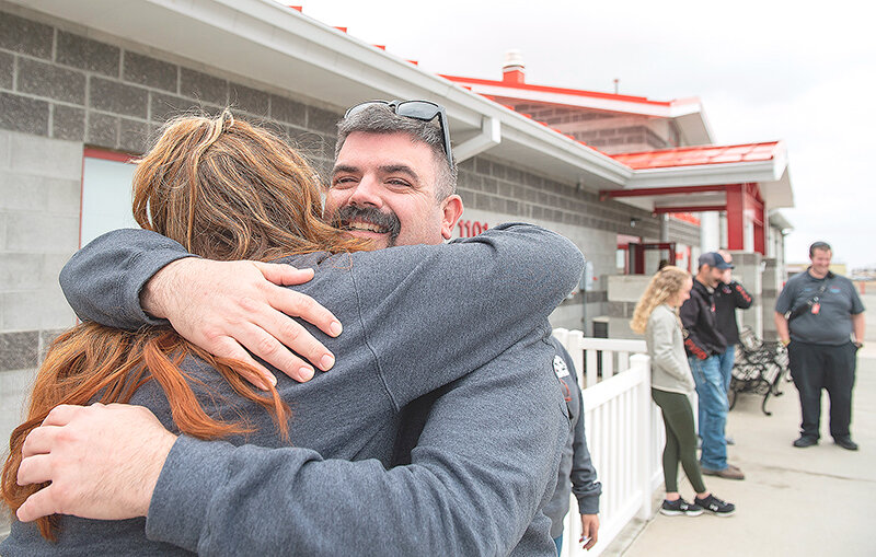 Geoff Hovivian gets a hug from McKennah Buck while other first responders wait in line to welcome Hovivian back to Powell after an extended stay in a New York hospital.