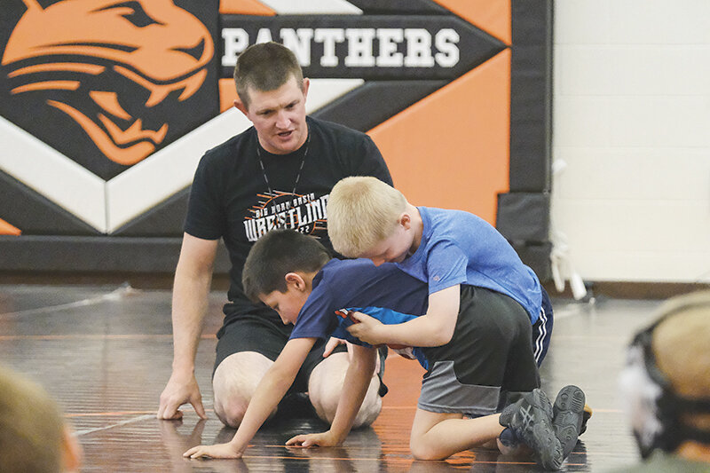 Coach Nick Fulton gives instructions to both Gabe Fulton (top) and Mikey Holland during the Powell High School wrestling camp on Thursday, June 1.