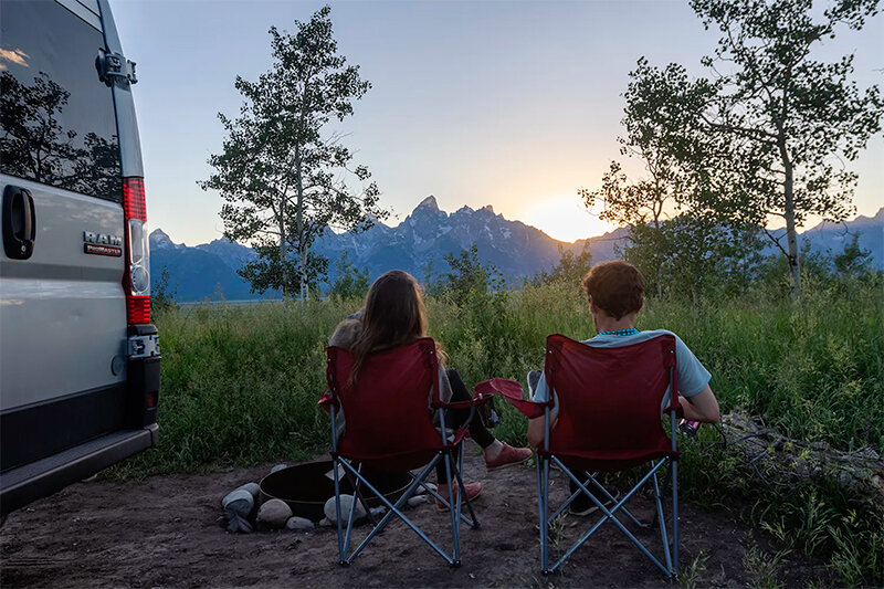 Campers Lexi Wilson and Andrew Yokel-Deliduka of Washington watch the sun set behind the Tetons at Shadow Mountain campground in July 2022 in the Bridger-Teton National Forest.