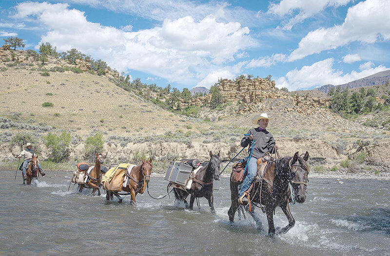Shoshone Back Country Horsemen members Danika (right) and Frank Fagan cross the North Fork of the Shoshone River with a string of horses en route to the club&rsquo;s 30th anniversary celebration after three days in the Shoshone National Forest clearing trails. The father and daughter team covered 54 miles in the days prior to the party.