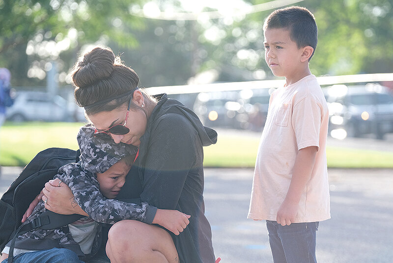 Kylar Miears (left) shares a hug with his mom, Roxanne Alcorn, before his first day of kindergarten at Parkside Elementary School on Tuesday while his brother Kaycen Miears looks on.
