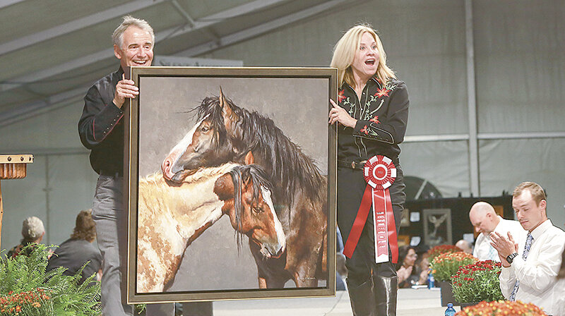 Volunteers Howard Thompson (left) and Gina Luttenegger carry an oil painting by Powell artist Mark McKenna during a previous Buffalo Bill Art Show &amp; Sale.