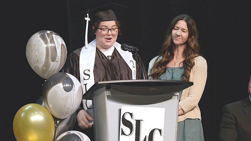 Nora Hart (left) addresses her SLC class of 2023 as one of her class&rsquo;s speakers while standing next to counselor Erin Curtis last May. Despite suffering a traumatic brain injury in the spring of 2022, Hart was able to graduate on time.