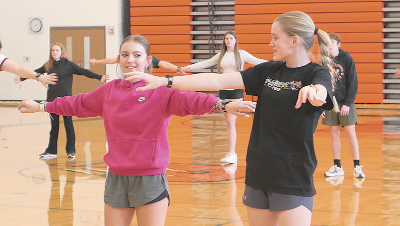 Alexis Helfrich (left) shares a look with Cambree Dicks while the two freshman participate in a Zumba class in late November as part of Powell High School&rsquo;s new group wellness and exercise class.