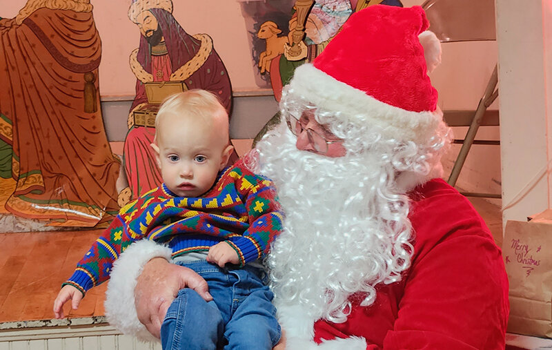 Powell resident Patrick Nylander, 14 months old, sits with Santa during the Sage Creek Community Club&rsquo;s 99th annual Christmas program.